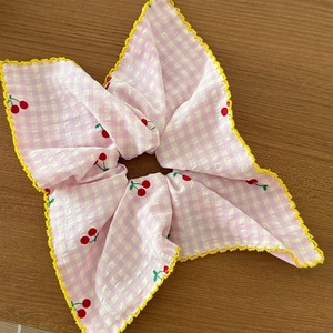 Détail d'un chouchou à carreaux roses avec cerises rouges et bordure crochetée