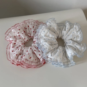Detail view of two mesh polka dot scrunchies with red and blue wavy trim edges