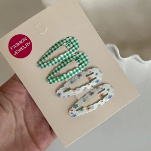 Detail view of 4-piece BB hair clips set with green plaid and colorful floral patterns