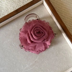 Macro detail of the 3D mauve fabric rose hair claw with elegant layered petals