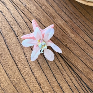 Fermaglio per capelli a stella marina rosa con petali e cristallo su sfondo in legno