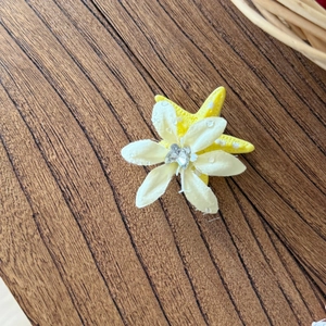 Dettaglio del fermaglio a stella marina con fiore in tessuto e cuore in cristallo