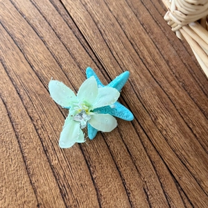 Dettaglio fiore in tessuto verde chiaro con stella marina blu su venatura del legno