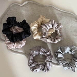 Set of five silky satin hair scrunchies in neutral tones displayed on a textured mat