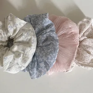 Set of four floral scrunchies in pastel blue and beige with elegant daisy patterns