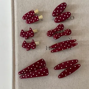 Detailed view of cherry red polka dot hair clips in various shapes on beige linen fabric
