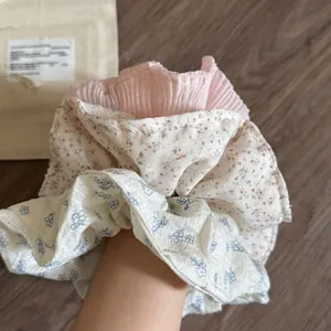 Detailed set of three floral scrunchies including pink pleats and daisy patterns worn on wrist