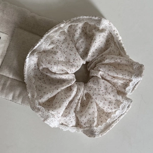 Detail of floral scrunchie with lace edge and delicate purple daisy print pattern