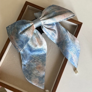 Detail einer Haarklammer mit Ölgemälde-Druck und elegantem Perlenanhänger am Schleifenband