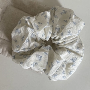 Detail of blue daisy floral scrunchie featuring soft pleated cotton fabric texture