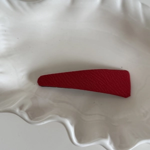 Détail d'une pince à cheveux en sergé rouge sur une assiette blanche pour un look artisanal