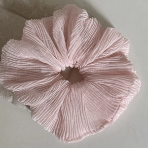 Close-up of a light pink oversized scrunchie with vertical pleated fabric texture