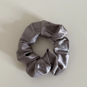 Close-up of silver-grey satin scrunchie showing smooth silk texture and ruched details