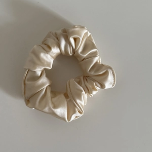 Detailed close-up of champagne satin scrunchie showing smooth pleated fabric and soft luster