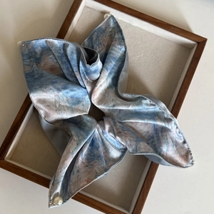 Detail eines blauen Seiden-Scrunchies mit Ölmalerei-Muster und eleganter Perlenverzierung