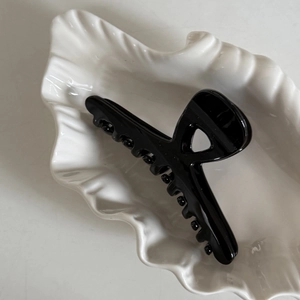 Pince à cheveux noire brillante avec design ajouré sur un plateau coquillage