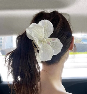 Détail d'une grande pince à cheveux orchidée blanche sur un chignon élégant de femme