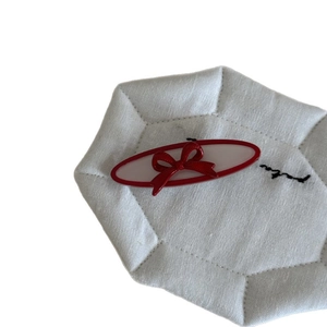French vintage red acetate bow hair clip with heart detail on a white quilted background