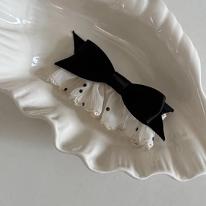 Elegant white lace polka dot bow hair clip with black satin on a white shell plate
