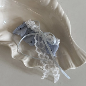Blue chiffon hair clip with white lace, bow design, and dots in shell tray