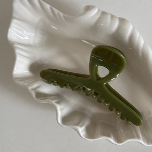Pince à cheveux vert olive brillant sur un plateau en céramique pour style élégant