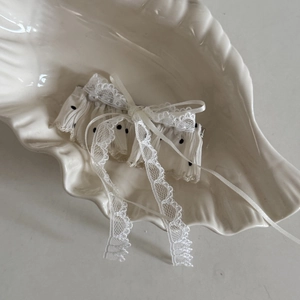 Macro shot of white lace polka dot bow hair clip with ribbons on a shell ceramic dish