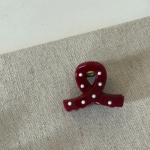 Detail shot of a small cherry red polka dot hair claw clip on a rustic burlap surface