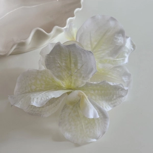 Détail de pinces à cheveux orchidée blanche artificielle avec motifs jaunes délicats