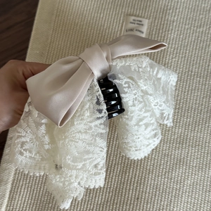 Détail de la pince à cheveux avec nœud en satin beige et dentelle blanche pour femmes