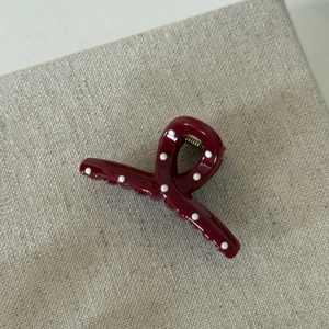 Macro view of cherry red polka dot hair claw clip on neutral textured fabric surface