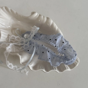 Detail of light blue polka dot lace garter with ribbon bow and faux pearl on shell tray