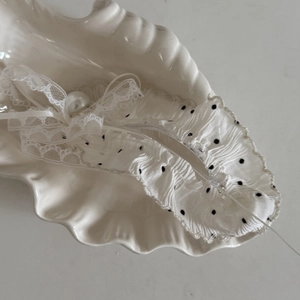 Detailed shot of white lace polka dot bow hair clip with pearl on shell plate