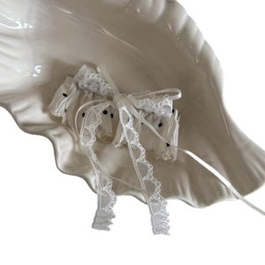 Elegant white lace bow hair clip with black polka dots and pearl accents in a ceramic tray