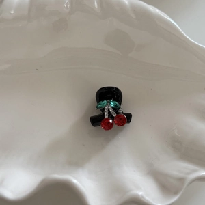 Detailed view of mini cherry hair claw clip with sparkling red and green rhinestones