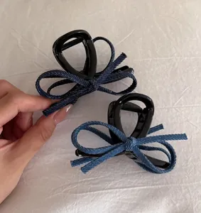 Detail of vintage denim bow hair claws with blue fabric texture and black glossy finish