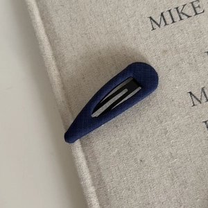 Minimalist navy blue fabric covered hair clip on a textured notebook background
