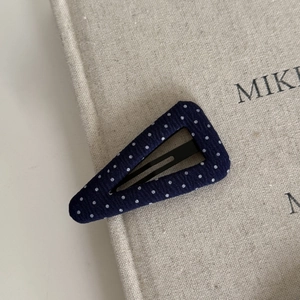 Detailed view of teardrop BB hair clip with navy blue white polka dot fabric texture
