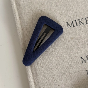 Close-up of navy blue polka dot fabric texture on triangle BB hair clip accessory