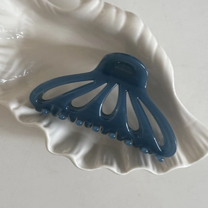 Dettaglio dell'elegante molletta per capelli blu navy a ventaglio su vassoio a conchiglia