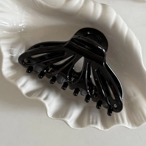Dettaglio di una grande molletta per capelli nera a ventaglio su un vassoio bianco