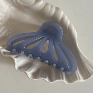 Dettaglio di una molletta per capelli blu opaca a forma di ventaglio in un piatto