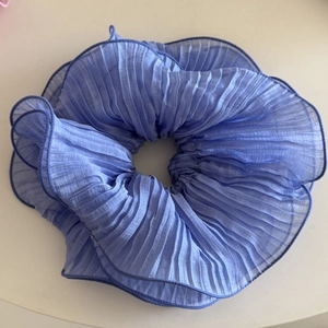 Dettaglio dell'elastico per capelli plissettato azzurro con bordi cuciti blu scuro