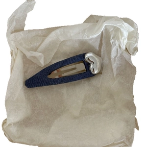 Fermaglio per capelli in denim blu con cuore argento su sfondo di carta bianca