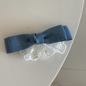 Detail van de zoete denimblauwe haarclip met witte kanten rand en metalen snavelclip