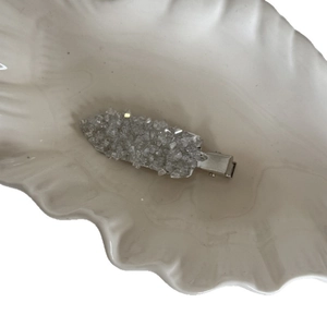 Exquisite crystal-encrusted BB hair clip with silver metal base on a white shell tray