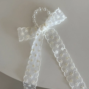 Detail van witte kanten haarclip met parelring en geborduurde bloemen voor meisjes