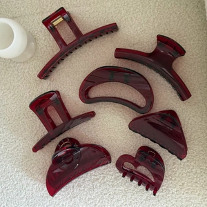 Set of seven French style burgundy resin hair claws in various geometric shapes on fabric