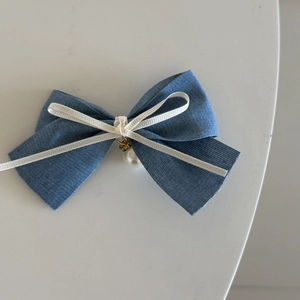 Macro-weergave van de denim blauwe haarstrik met wit kant en een parelvormige hanger