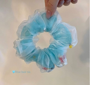 Détail d'un chouchou en organza bleu clair avec perles blanches et petits charmes de poissons