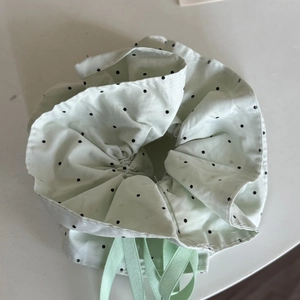 Detail of light green polka dot fabric hair scrunchie with matching drawstring ribbons
